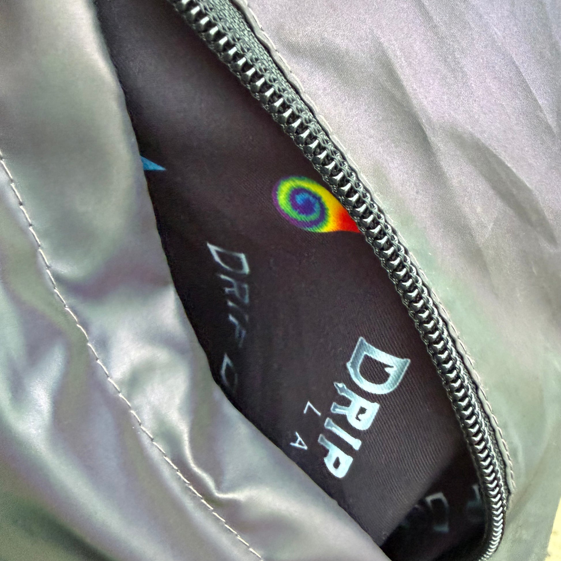 Reflective parachute pants from Drip Drop Labs featuring shiny fabric, elastic waistband, and relaxed fit for urban style.
