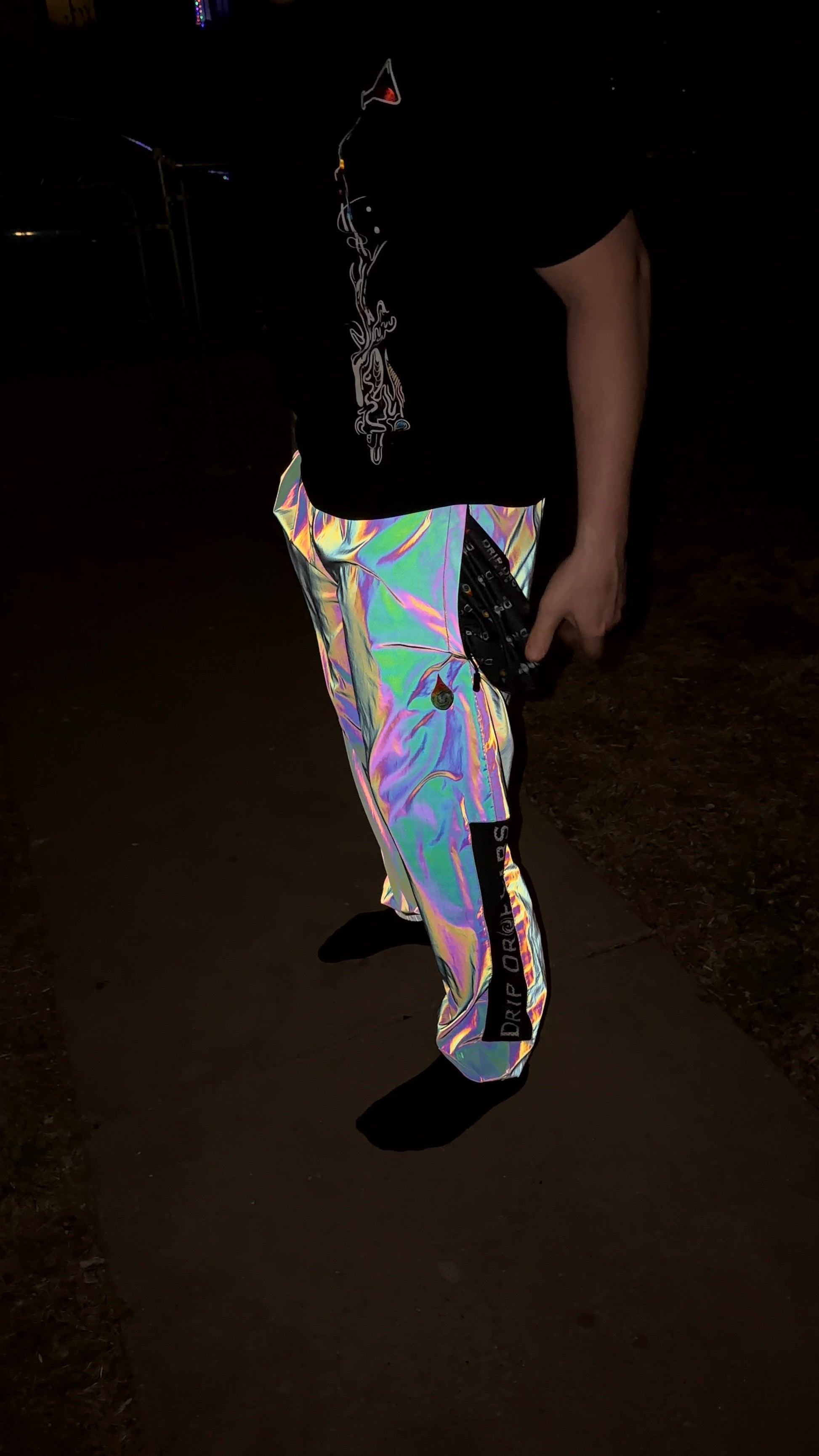 Reflective parachute pants by Drip Drop Labs featuring shiny fabric, adjustable waistband, and a relaxed fit for streetwear style.