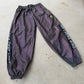 Reflective parachute pants by Drip Drop Labs showing shiny, lightweight fabric with adjustable waist and tapered legs.
