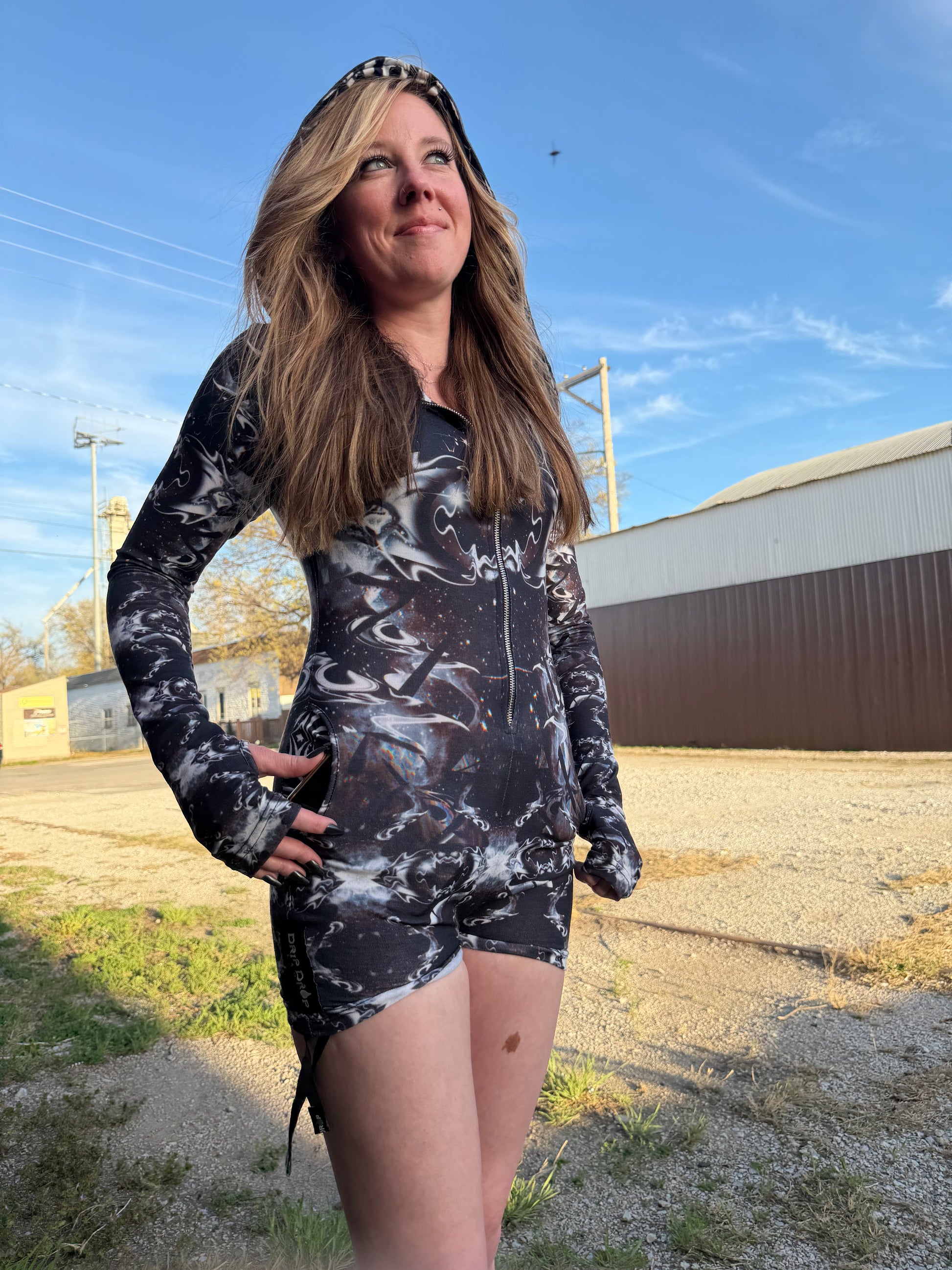 Dark galactic rave romper with hood from Drip Drop Labs featuring vibrant space-themed patterns and luminous fabric details.
