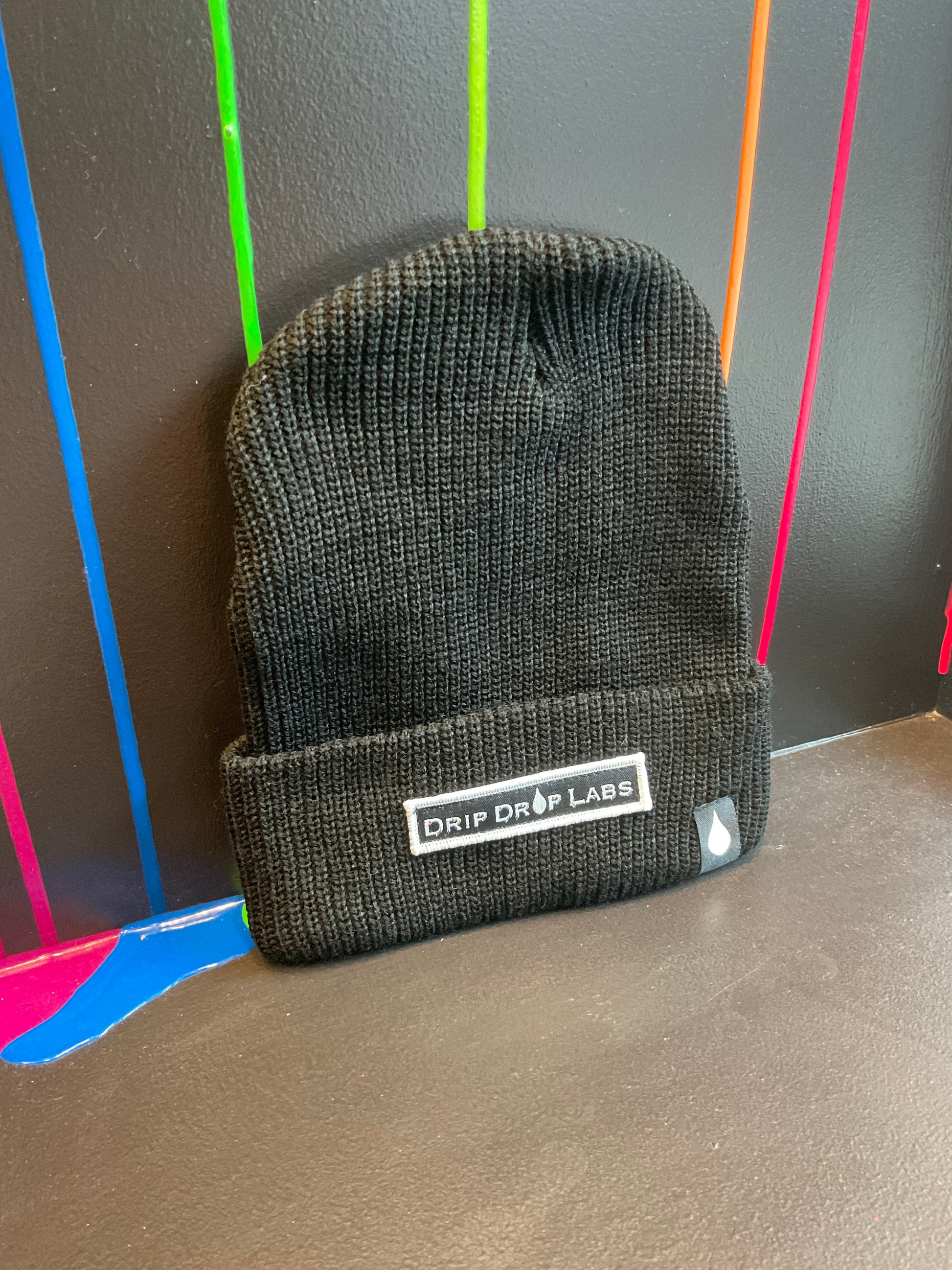 Black Drip Drop Labs beanie hat with embroidered logo, cozy knit material, designed for warmth and casual style.