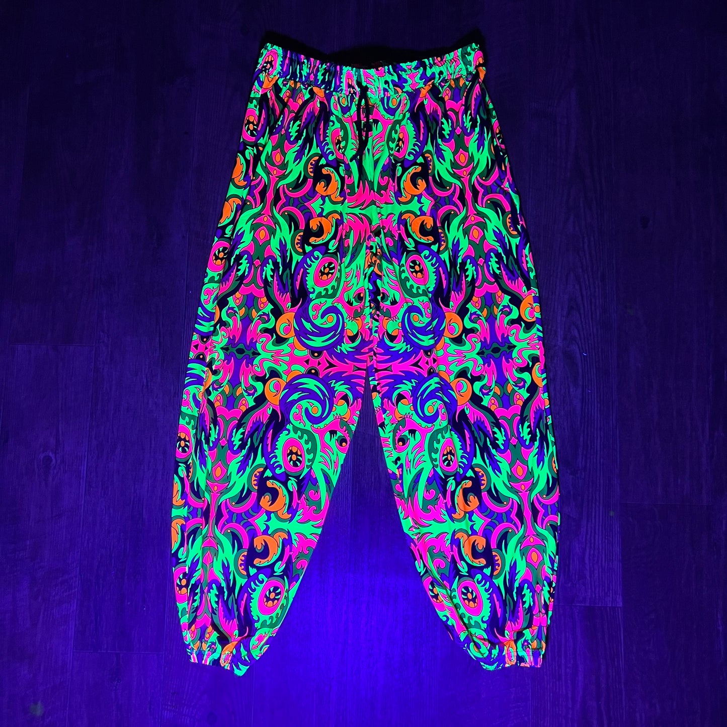 Drip Drop Labs Wild Forest parachute pants in green camouflage fabric with relaxed fit and drawstring waist.