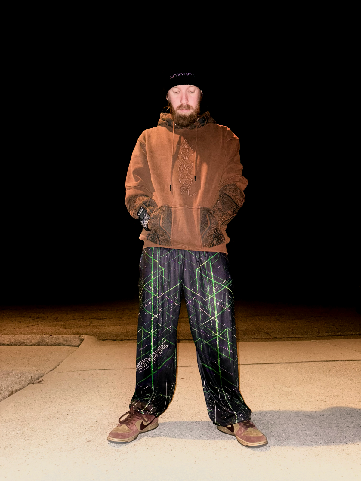 Model wearing Xenotype parachute pants in urban streetwear setting