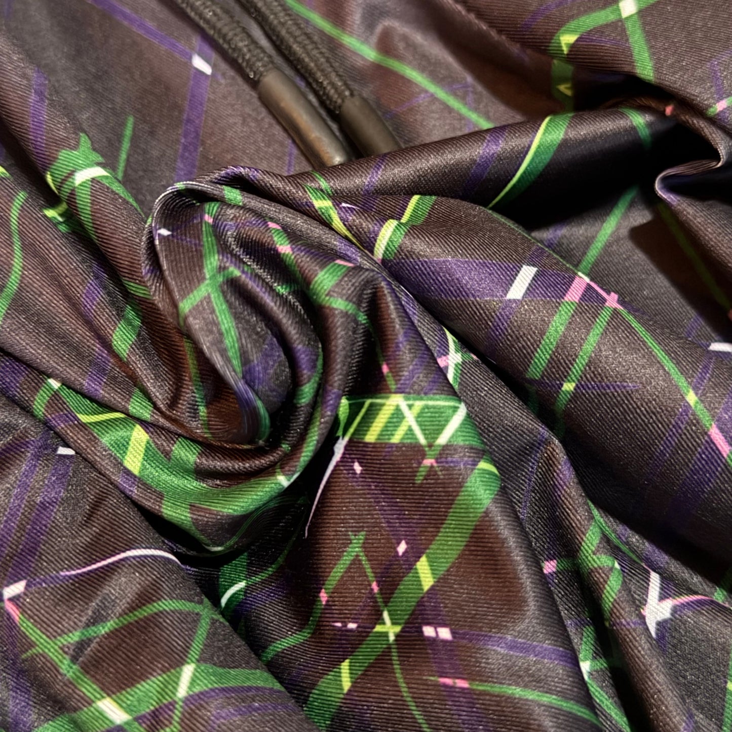 Close-up of luxury fabric with green and purple lines on a dark background