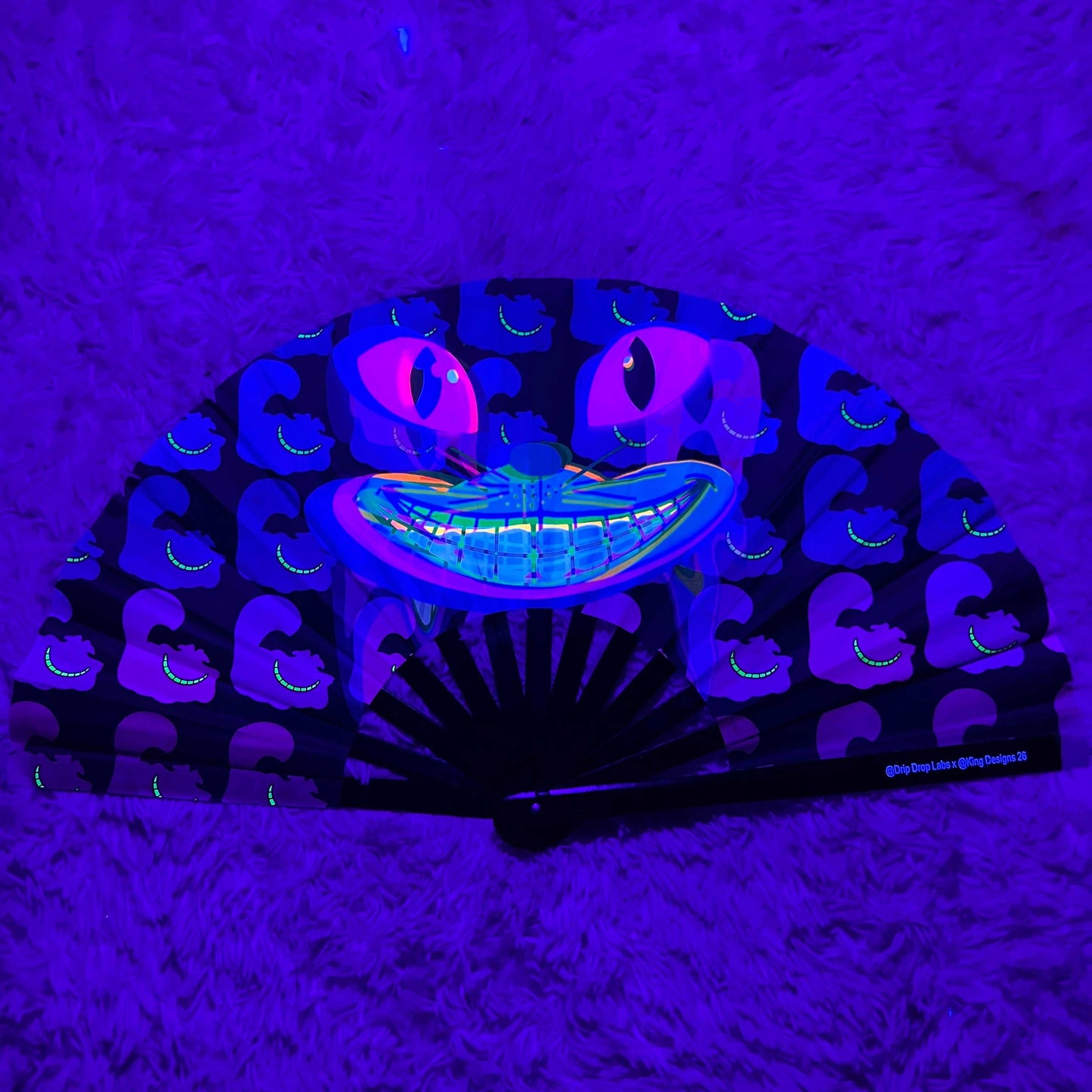 CheshireDrip Glow Fan by Drip Drop Labs with colorful LED lights, portable handheld fan for cooling and style.